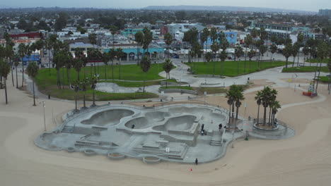 Sobre-El-Patinaje-De-La-Playa-De-Venecia-Casi-Vacío-Debido-Al-Parque-De-Bloqueo-Del-Coronavirus-Cerca-De-La-Playa-De-Los-Ángeles,-Toma-Aérea-De-Gran-Angular