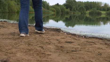 Solitary-person-walking-in-golden-sand-by-lakeside-wide-shot