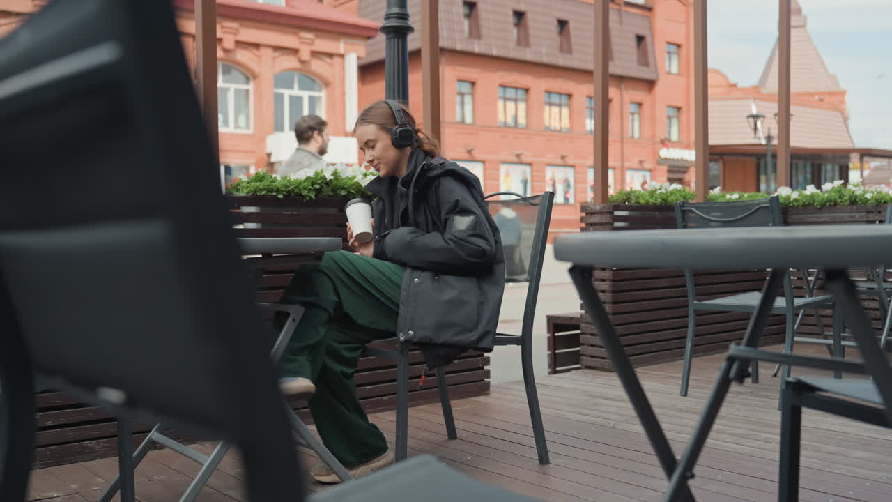 Kvinde nyder livlig gademusik udenfor, kvinde slapper af midt i livlige udendørs cafélyde og musik, kvinde finder fritid og afslapning, mens hun lytter til livlige gade- og cafémelodier