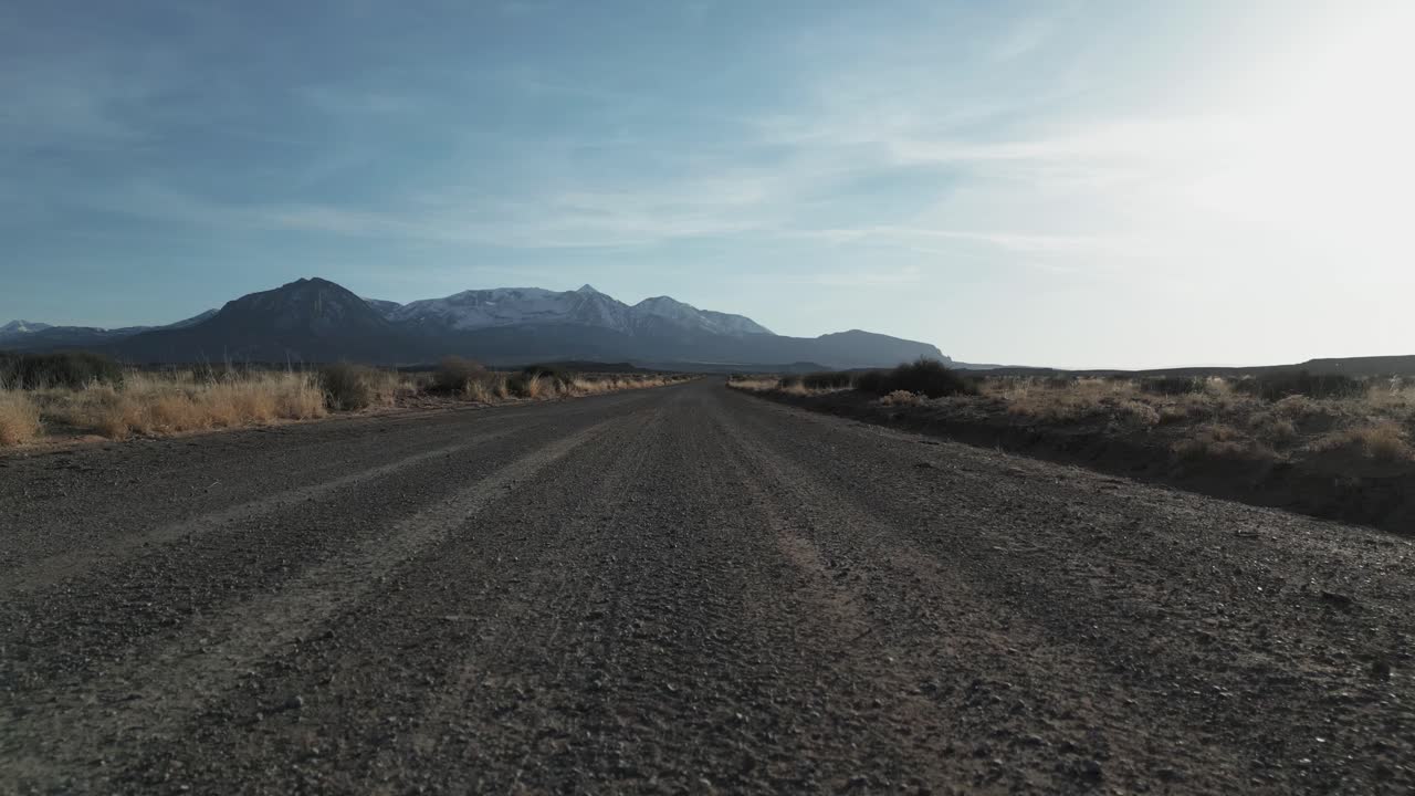 Vista aérea de la inmensidad del desierto de Utah siguiendo el camino de tierra con montañas al fondo, EE. UU.