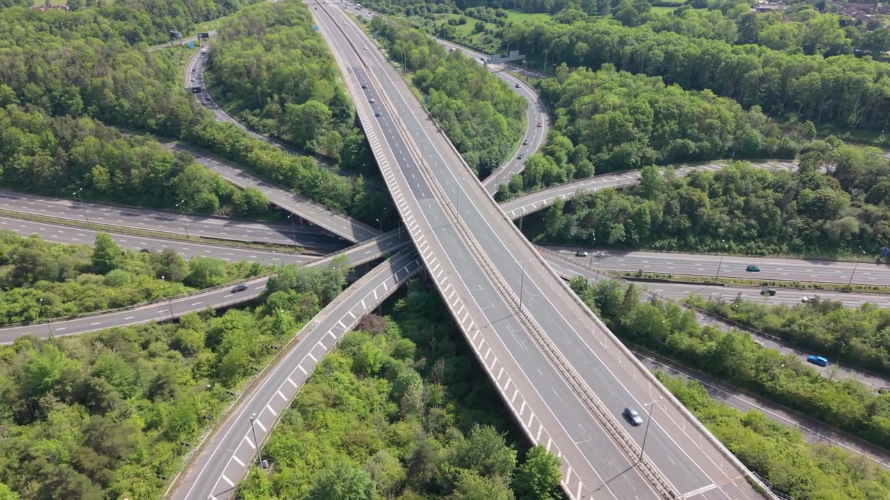 Una perspectiva aérea captura un vasto cruce de autopistas durante el día. Los vehículos navegan por las carreteras de varios niveles y las rampas de conexión.