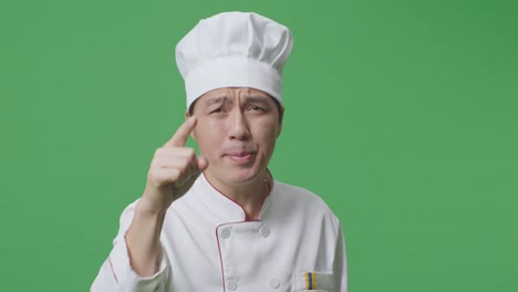 un hombre asiático, un chef, gritando a la cámara mientras está de pie en el estudio de fondo de la pantalla verde.