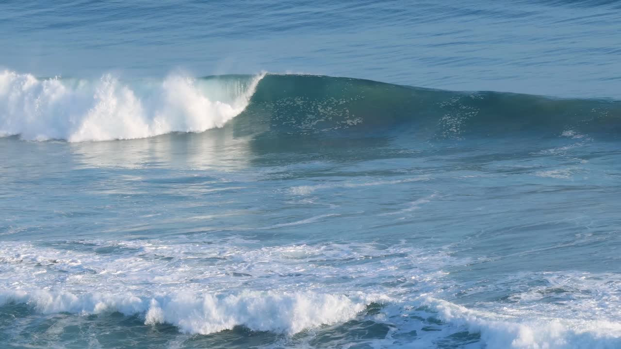 A series of ocean waves gracefully cresting and breaking, showcasing the rhythmic beauty of the sea.