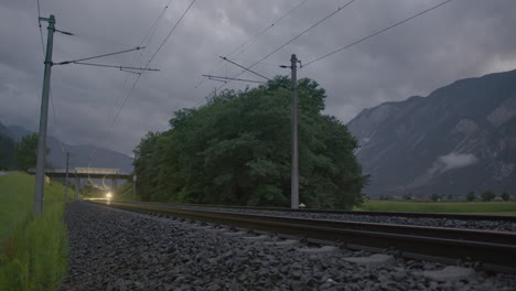 tren que se acerca a las vías al anochecer
