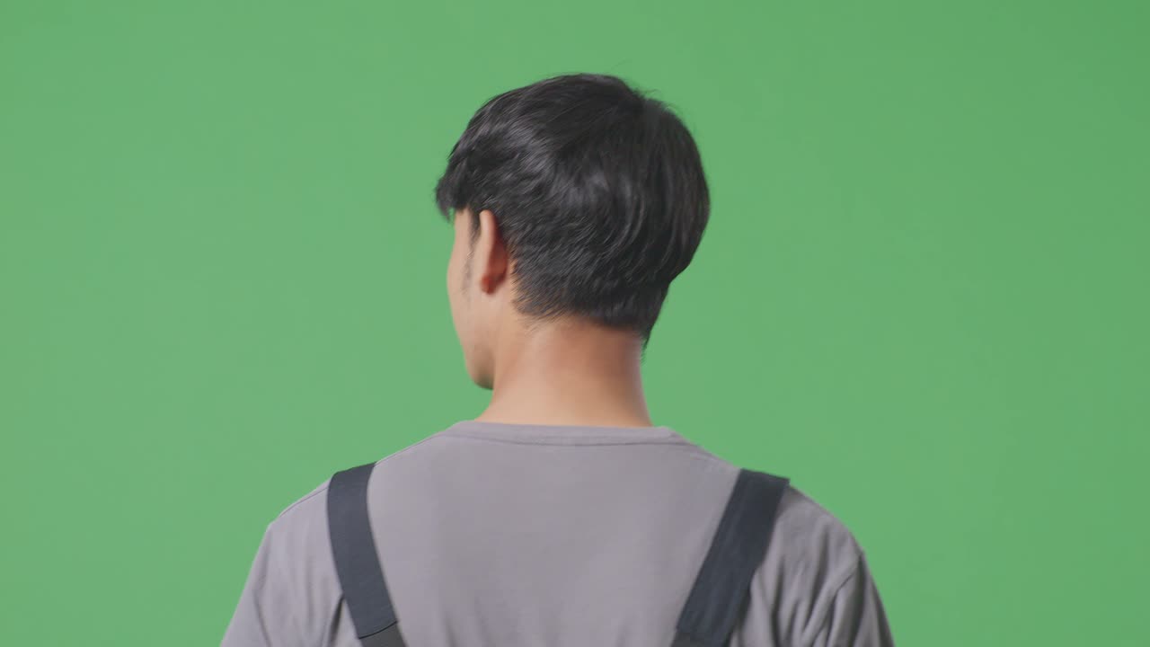 동양인 노동자가 녹색 스크린 배경 스튜디오에서 고 둘러보고 있습니다.