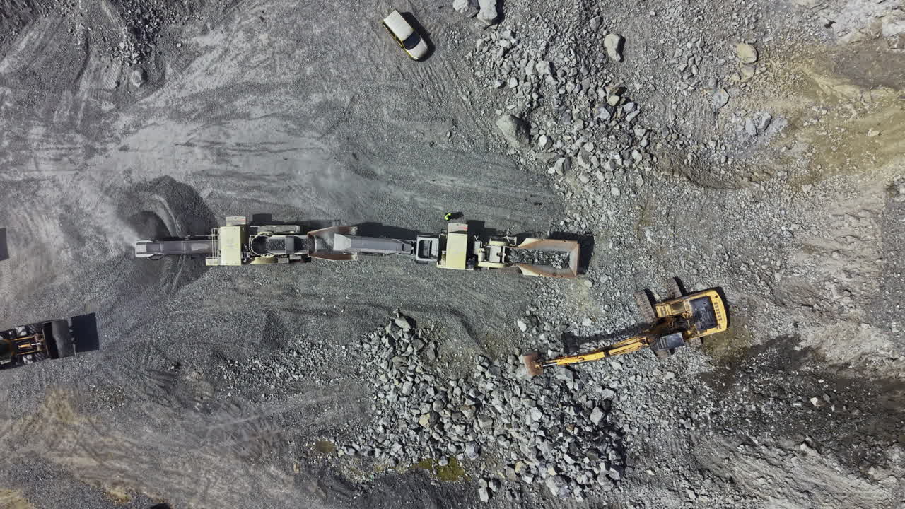 Granite quarry workers using heavy machinery for stone extraction and processing at a mining site