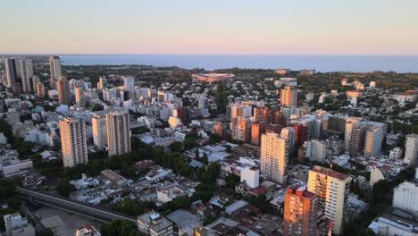 dolly in flying over belgrano neighborhood buildings at sunset, rio de la plata river in background, buenos aires, argentina