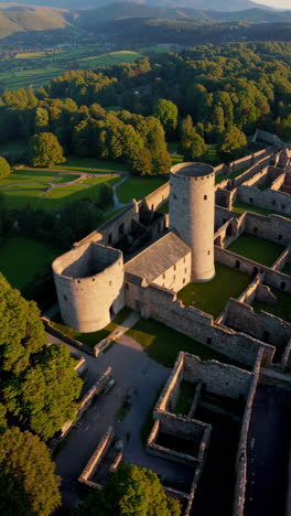 aerial view of expansive castle ruins in a lush green landscape during golden hour