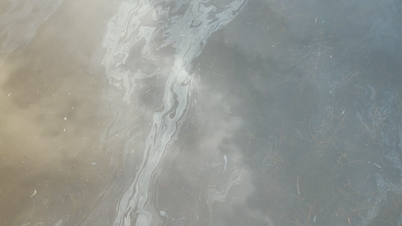 película de gasolina en la superficie del agua que refleja las nubes