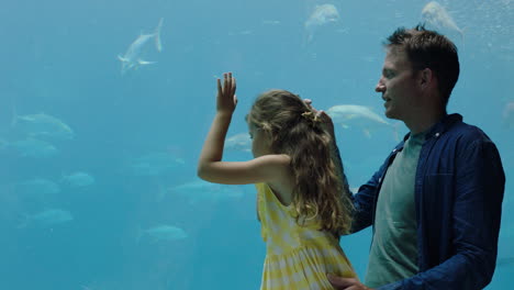 Padre-Con-Niña-En-El-Acuario-Tomando-Fotos-De-Peces-Usando-Un-Teléfono-Inteligente-Disfrutando-De-La-Vida-Marina-Nadando-En-El-Tanque-Divirtiéndose-En-El-Oceanario-Compartiendo-En-Las-Redes-Sociales