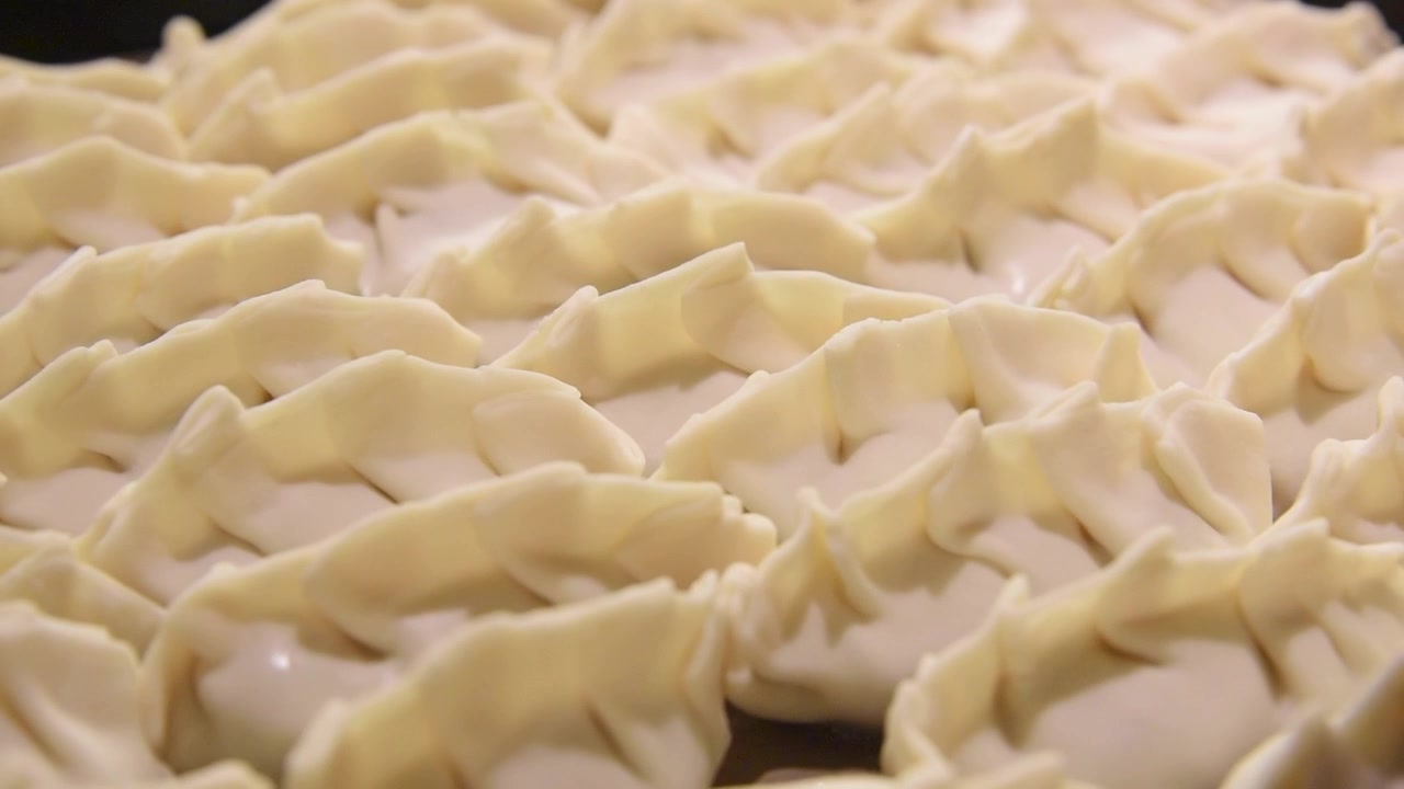 Molti ravioli gyoza giapponesi crudi sfrigolano in una padella calda. Preparazione casalinga di autentica cucina asiatica per una deliziosa cena