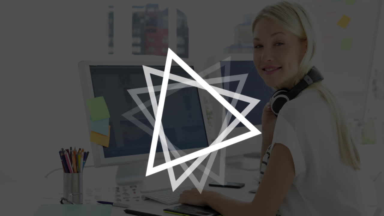 Woman working at desk with glowing triangle animation over computer screen