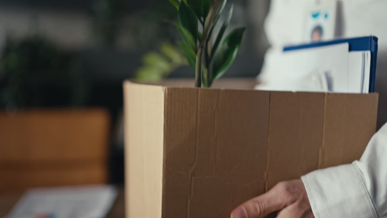 Cardboard box with plant and documents, representing leaving job or office relocation