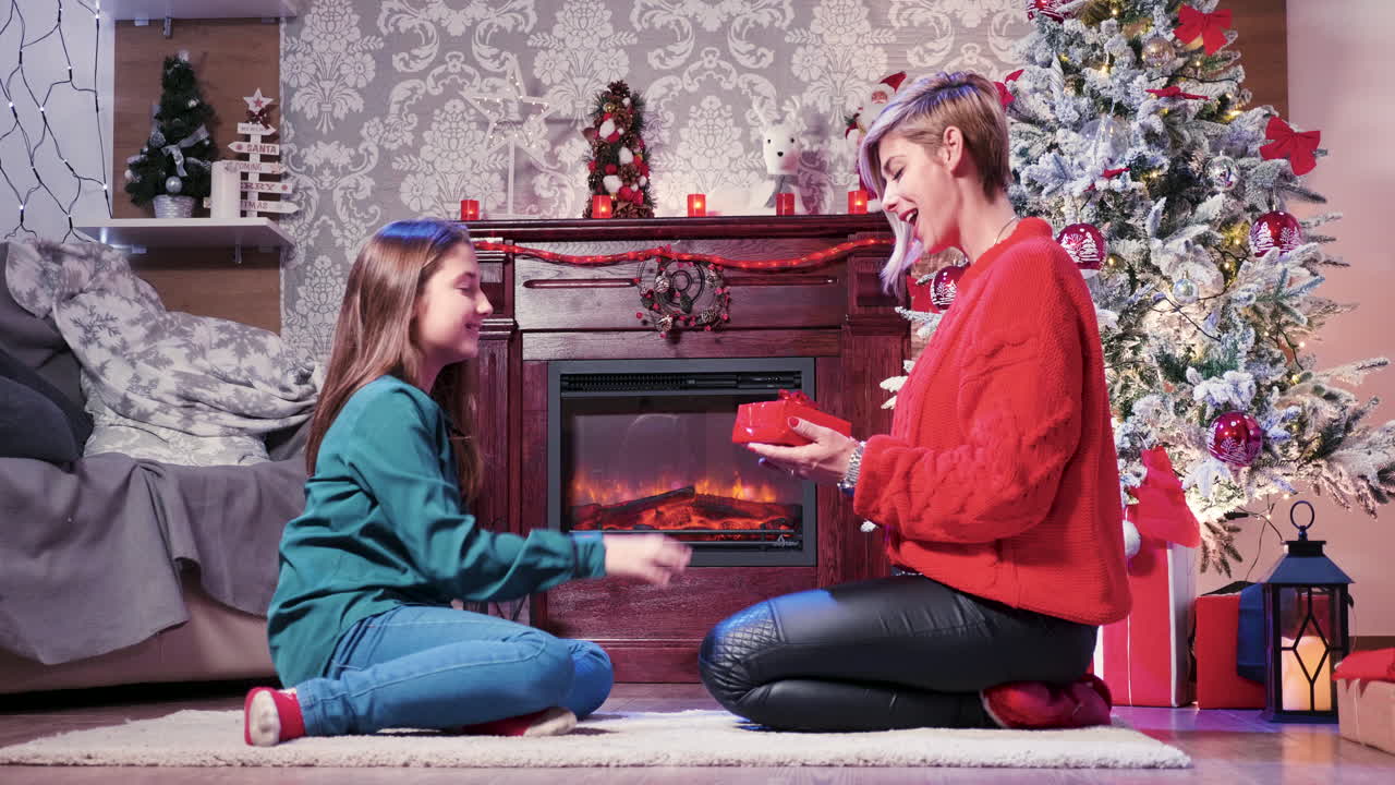A mother and daughter enjoying Christmas time by the fireplace