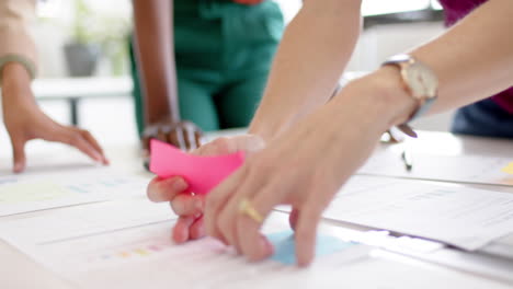 hands of diverse creative female colleagues brainstorming in meeting in board room, slow motion