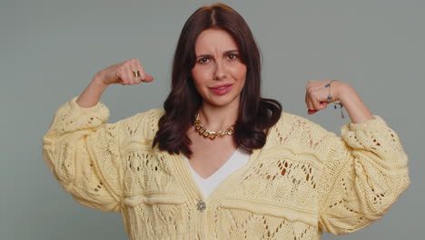 mujer bonita en forma deportiva que muestra bíceps y parece confiada, sintiendo poder fuerza éxito ganar