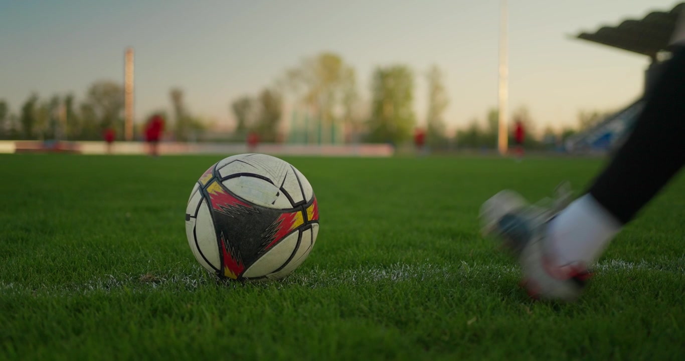 Spiller sparker fodbold på grøn græsbane