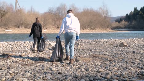 teamwork cleaning plastic on the beach. volunteers collect trash in a trash bag. plastic pollution and environmental problem concept. voluntary cleaning of nature from plastic. greening the planet