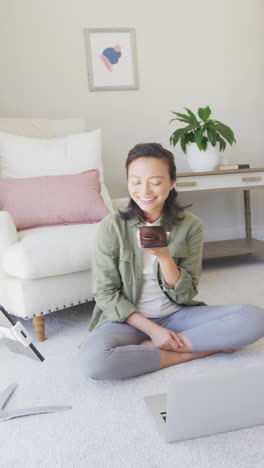 Vertical video of happy asian woman using smartphone in bedroom, in slow motion