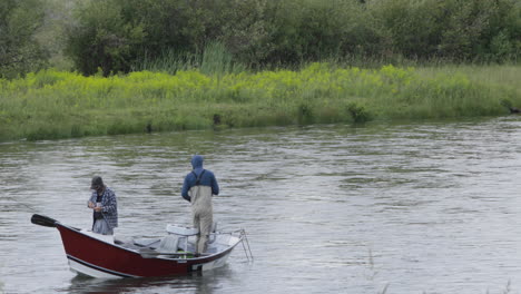 two friends fly fishing from a small bass boat along snake river chester idaho.