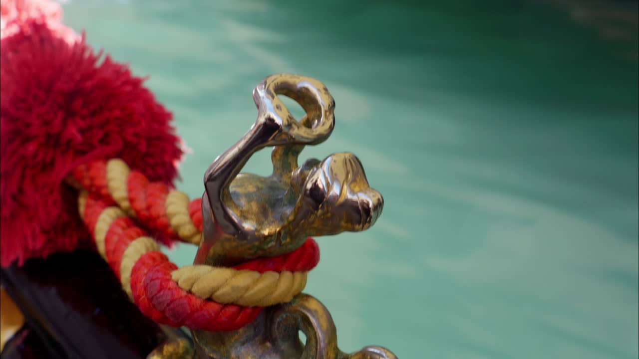 Decorazione metallica ornata di gondola con corda colorata sull'acqua del canale