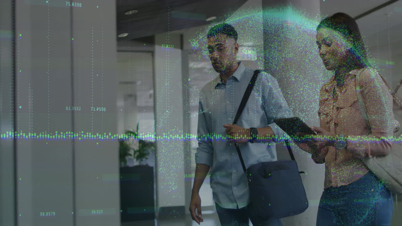 Colleagues walking down corridor, reviewing tablet while floating tech graphs visualizing data