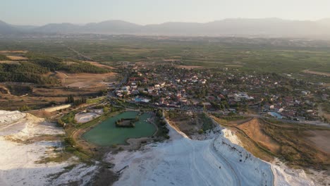 aerial view of pamukkale town turkey under white limestone hills, popular tourist destination on sunny day, drone shot