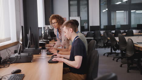 group of college students with tutor studying computer design sitting at monitors in classroom