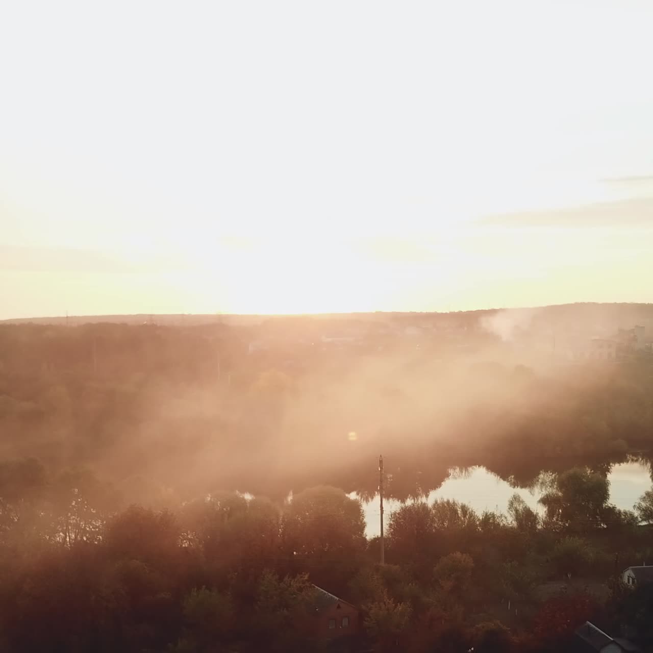 smoke are enveloping a river as a result of a fire after a drought on the background of power station into the distance. Aerial view