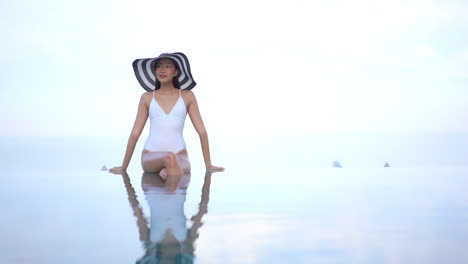 Regla-De-Los-Tercios-Una-Hermosa-Joven-Con-Un-Traje-De-Baño-Blanco-De-Una-Pieza-Y-Un-Sombrero-De-Paja-Flexible-Está-Al-Borde-De-Una-Piscina-De-Borde-Infinito