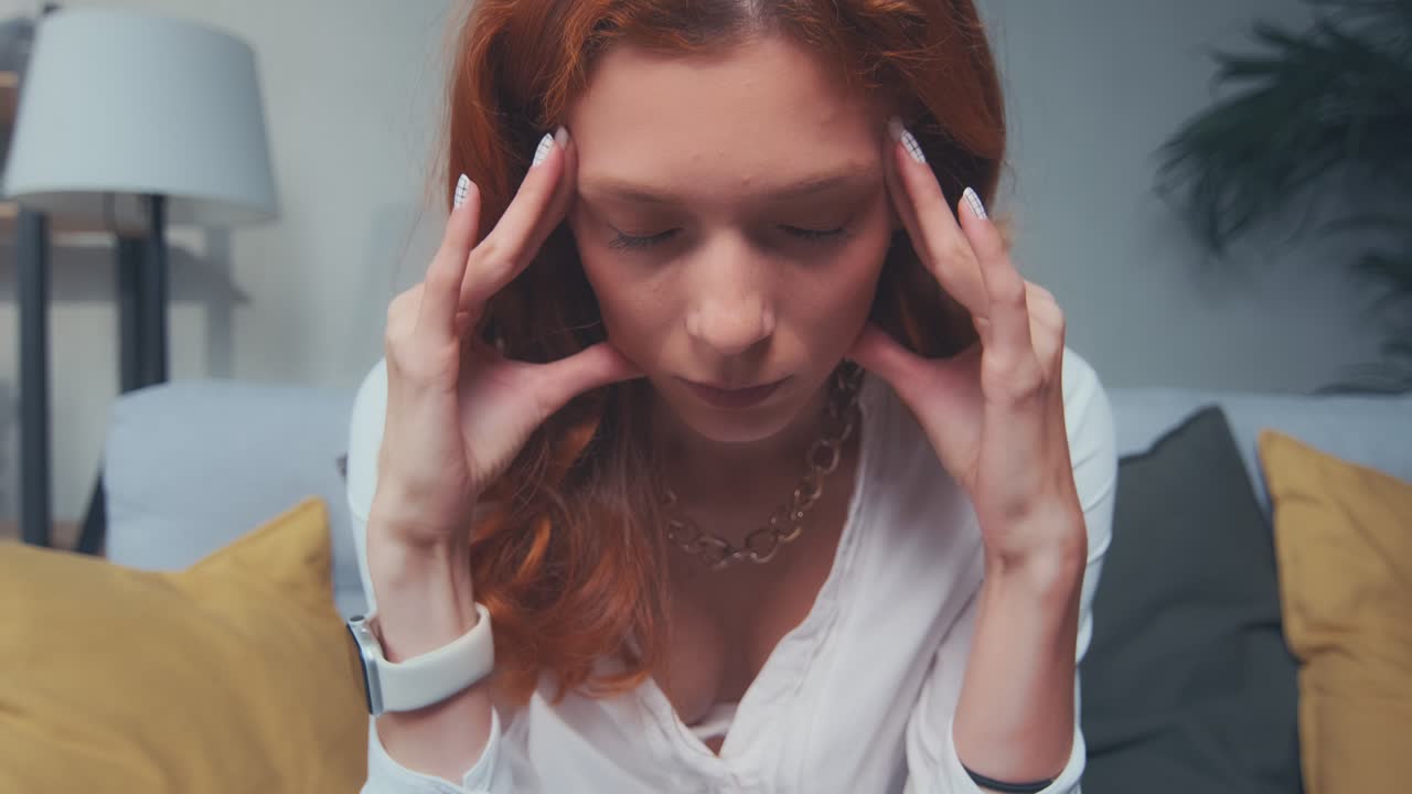 un primer plano de una joven pelirroja molesta que se enfrenta a un dolor de cabeza y una migraña.