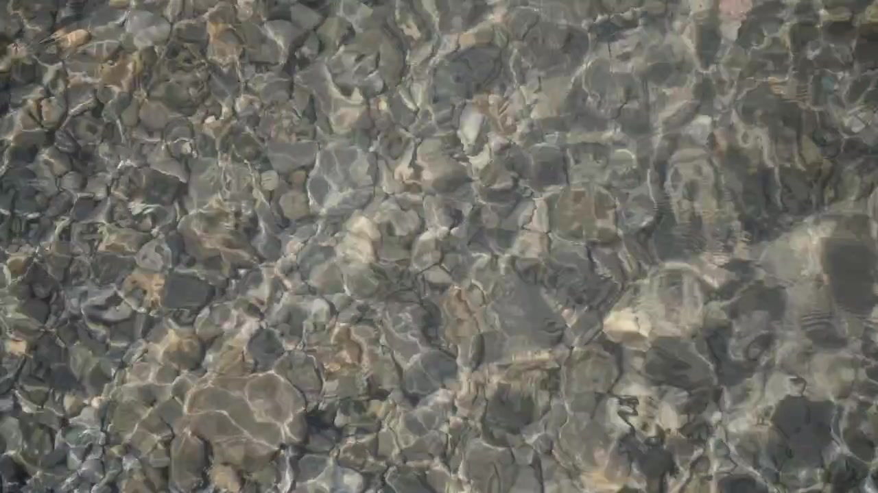Overhead View of Clear Water with Ripples and Pebbles