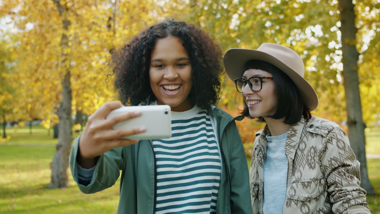 Two young women taking a selfie in an autumn park