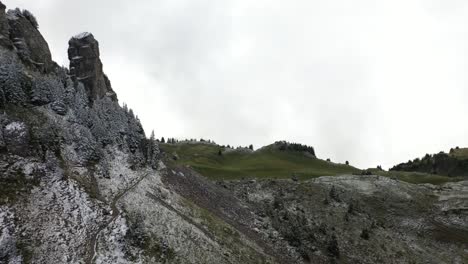 Dramatic-and-majestic-peak-with-trees-covered-in-snow,-fading-gradually-to-green-fields-in-the-quiet,-empty-and-serene-nature-of-Schynige-Platte,-Switzerland