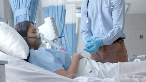 male doctor in gloves injecting drip of biracial female patient in bed with syringe, slow motion