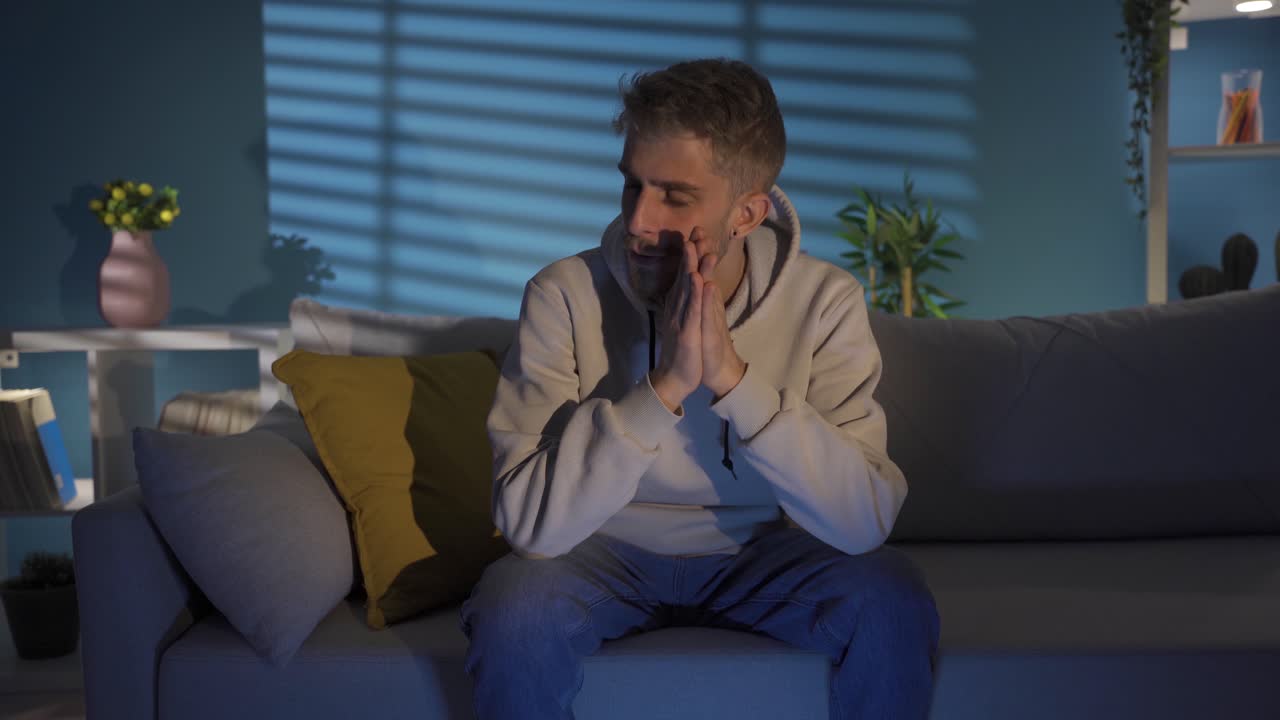 Depressed Young Man with Hand on Face Looking Blank at Home All Day.