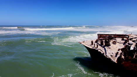 rusted old shipwreck battered by waves on cape agulhas coastline, aerial