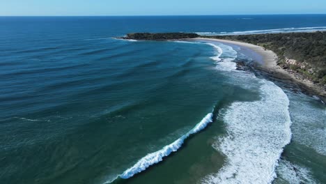 revealing drone view of larges waves breaking on a rugged coastal beach