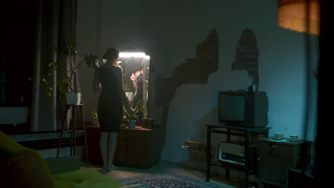 Woman getting ready by a lighted mirror at night