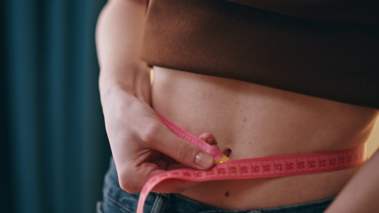 manos midiendo la cintura femenina con cinta de primer plano. mujer sonriente feliz disfrutando