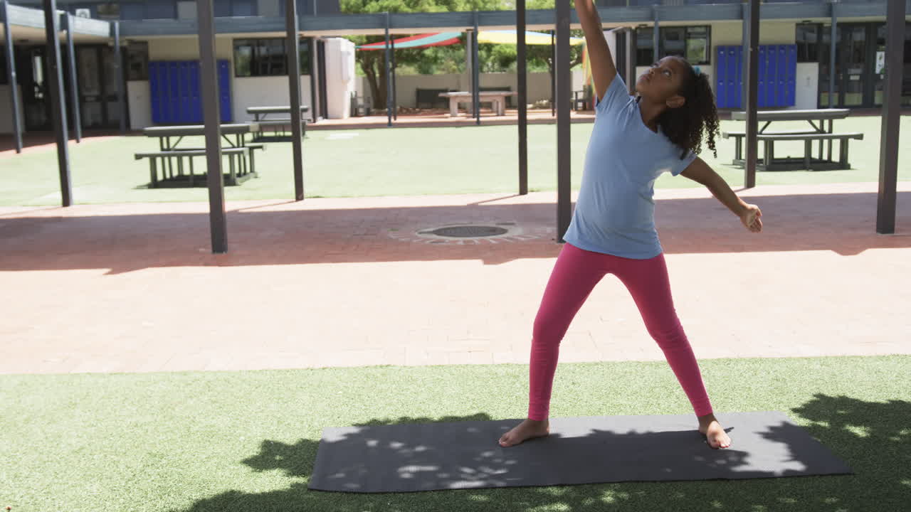 chica biracial practicando yoga al aire libre en una alfombra con espacio de copia en la escuela