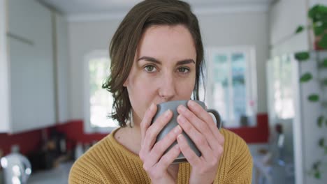 retrato de una mujer caucásica bebiendo café y mirando a la cámara