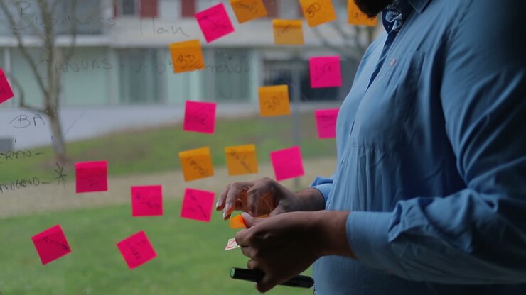 Male hands glueing sticky notes on window.