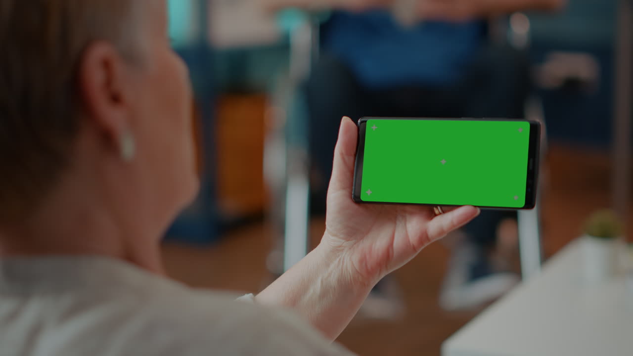 Senior woman holding a mobile phone with a green screen