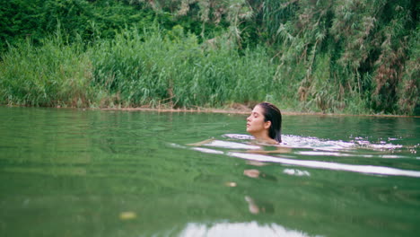 relaxed girl swimming green waters. seductive naked woman floating lake alone