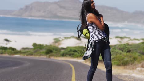 African-american-woman-picking-up-her-backpack-walking-on-road