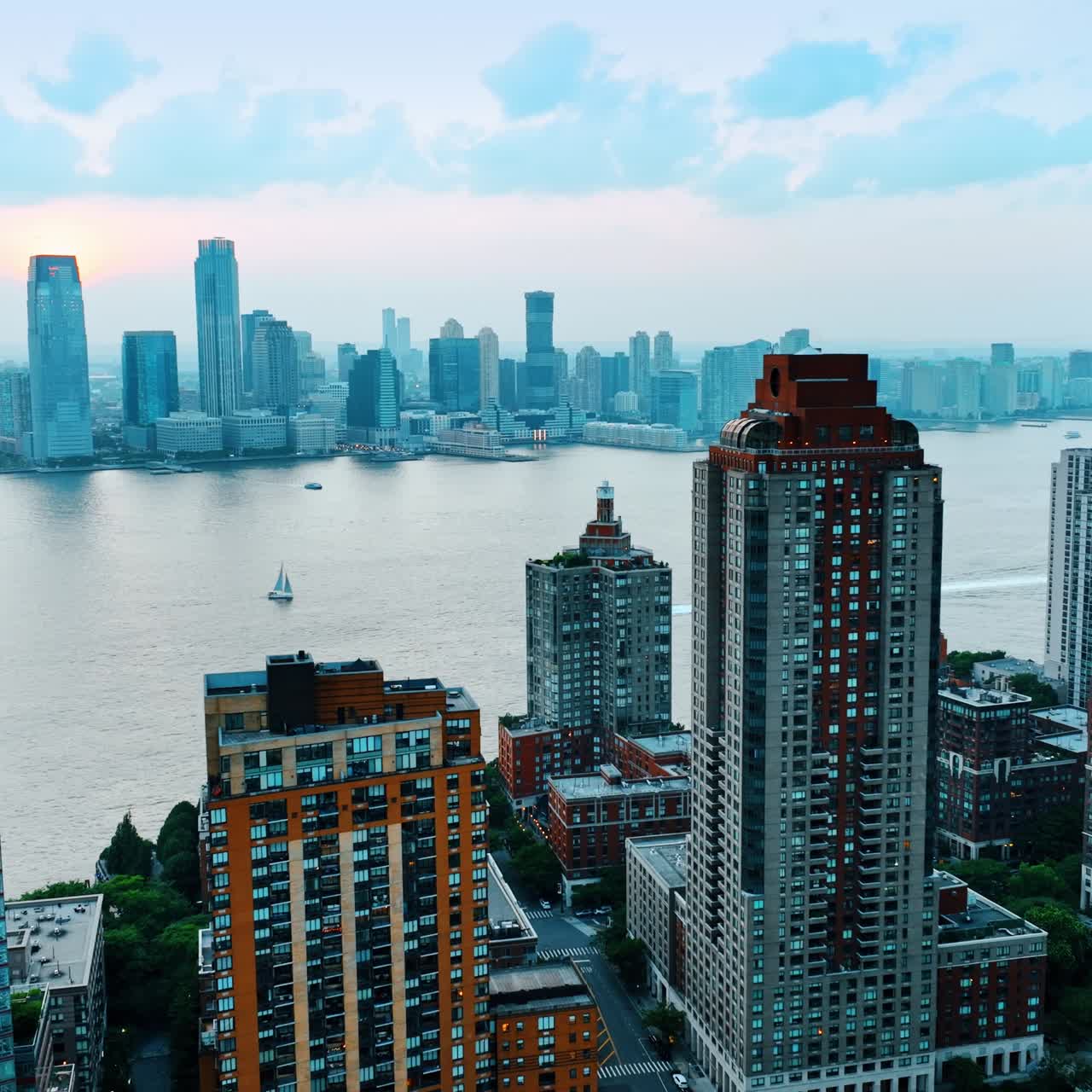 Looking at New York skyscrapers from across the river. Majestic building on both sides of Hudson. River transport is on water. Top view