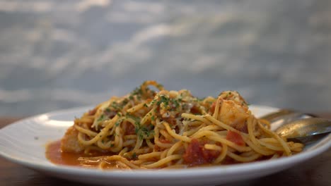 a little girl eats tomato seafood spaghetti in a restaurant. tilt shot from top to bottom.