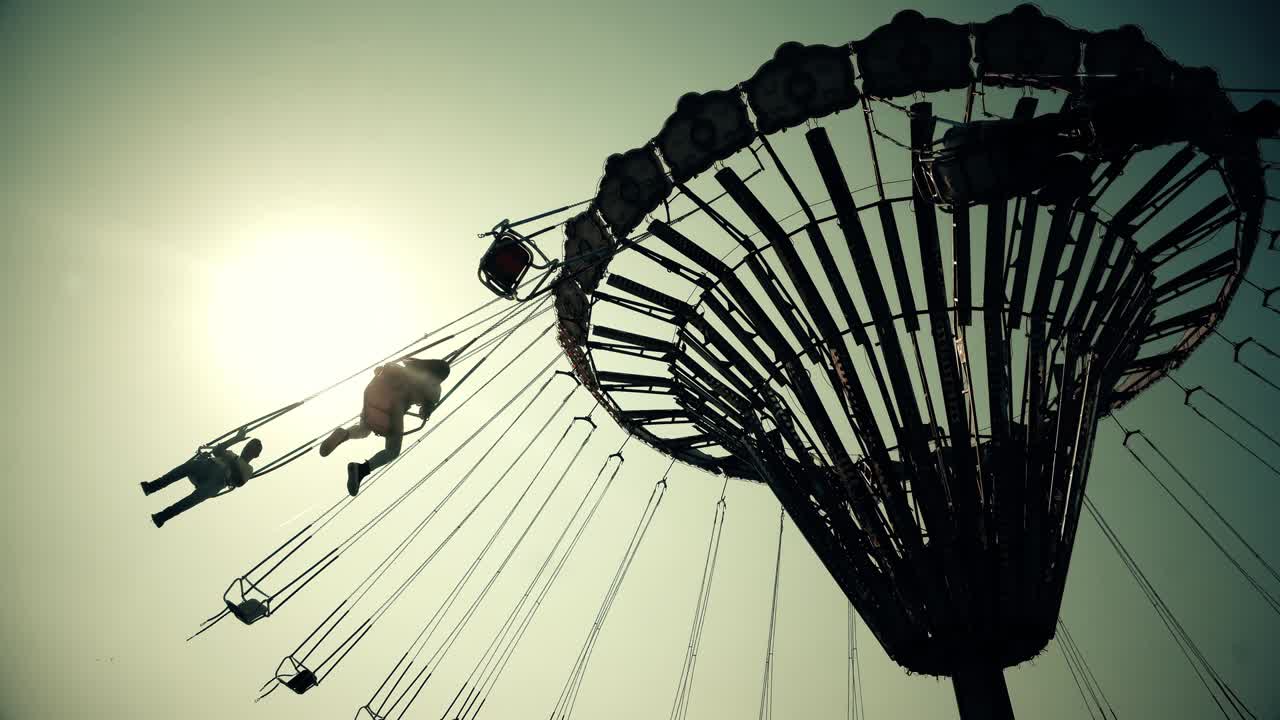 летает в воздухе на карусели с закатом солнца на заднем плане