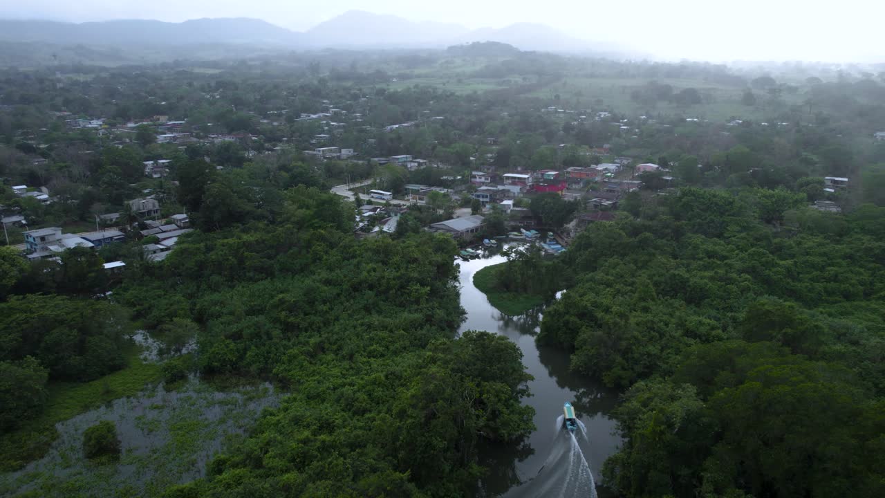 tilt up camera movement with view of a boat sailing through a river heading towards the mountains at sunset in Veracruz, Mexico